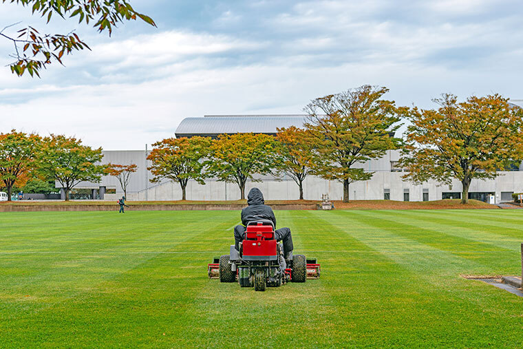 man on lawnmower in front of corporate building