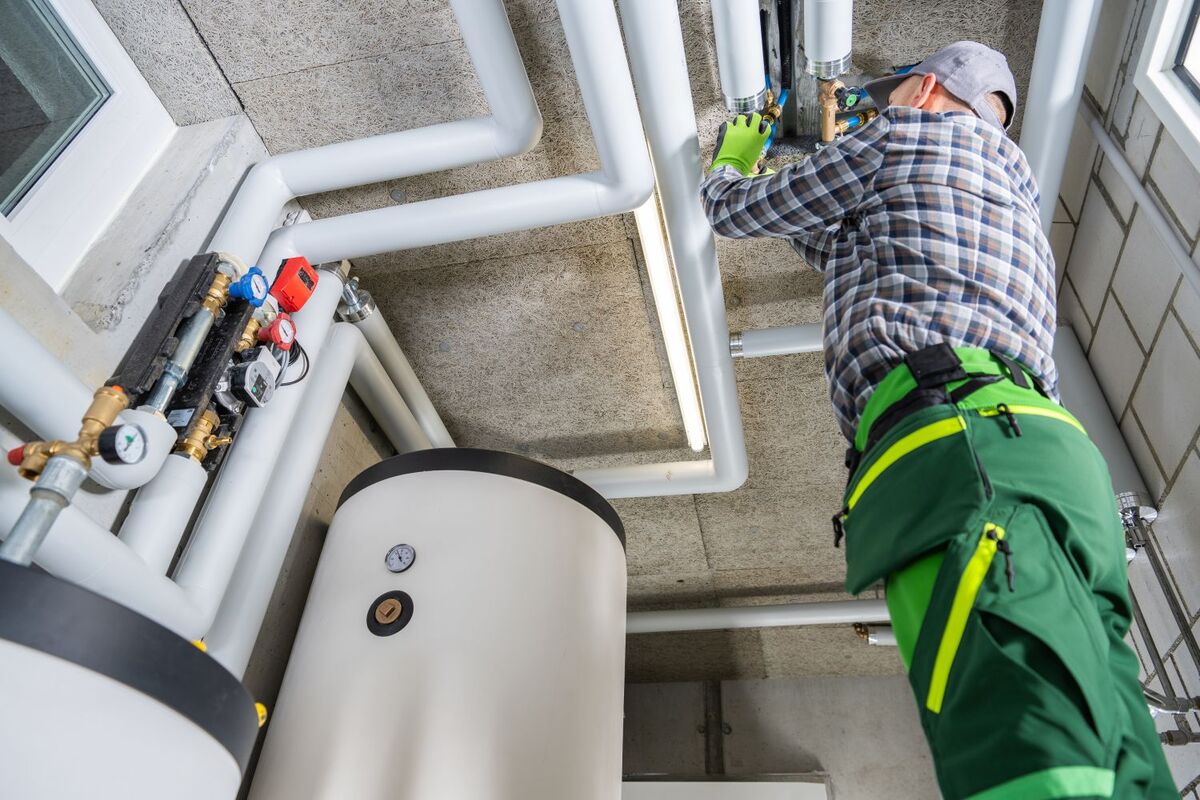 Plumber working on pipes with water tank
