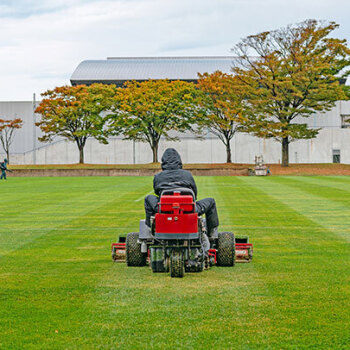 man mowing lawn in front of corporate building
