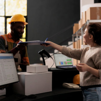 Woman handing worker a clipboard in warehouse